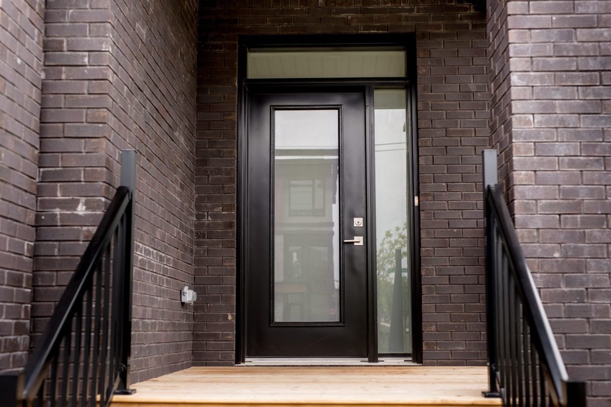 exterior view of brick building with black single door and full pane glass side lite